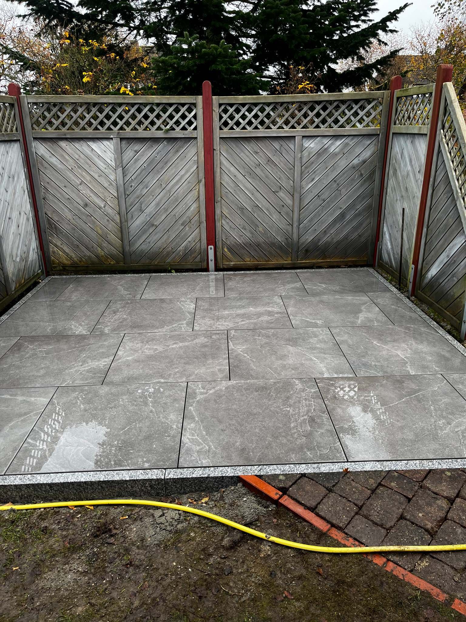 Neue Terrasse mit grauen Feinsteinzeug-Platten und Granitkante
